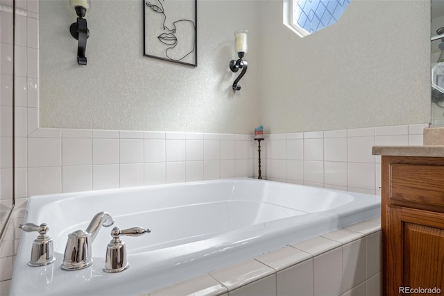 full bathroom with a garden tub, a textured wall, and vanity