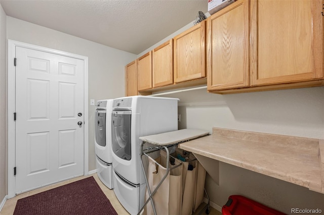 laundry area featuring cabinet space, a textured ceiling, and washing machine and clothes dryer