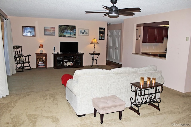 living area featuring a textured ceiling, carpet floors, and a ceiling fan