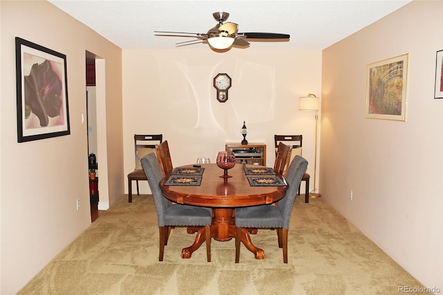 dining area featuring ceiling fan and light colored carpet