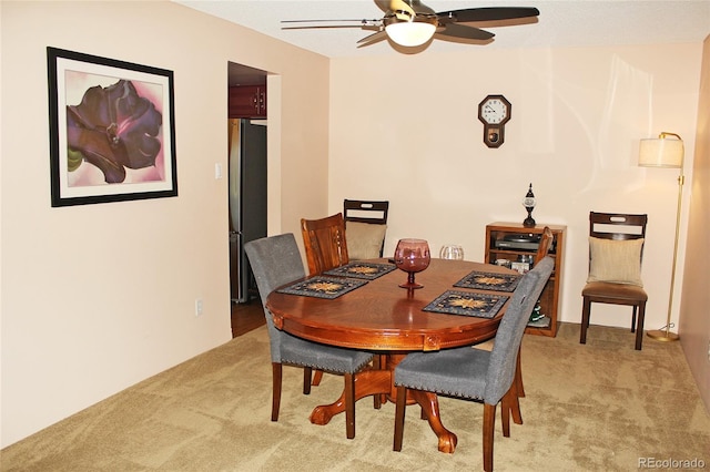 dining space with light carpet and a ceiling fan