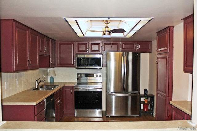 kitchen featuring stainless steel appliances, a sink, light countertops, backsplash, and reddish brown cabinets