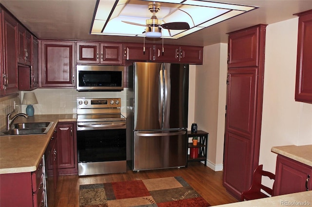 kitchen with stainless steel appliances, dark wood-style flooring, a sink, and dark brown cabinets