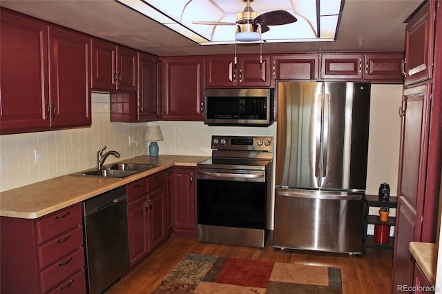 kitchen with reddish brown cabinets, dark wood-style floors, stainless steel appliances, light countertops, and a sink