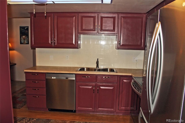 kitchen with reddish brown cabinets, decorative backsplash, stainless steel appliances, light countertops, and a sink