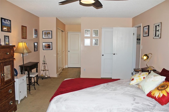 bedroom with a ceiling fan, a textured ceiling, and light colored carpet