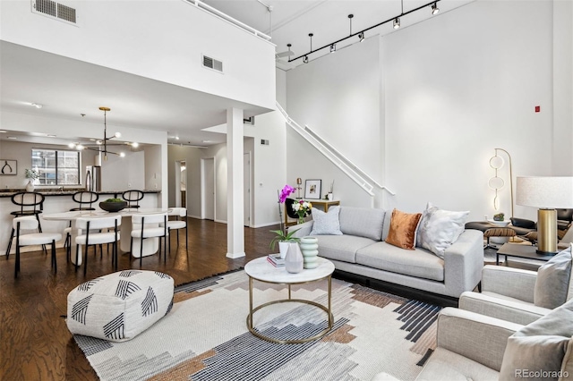 living room with track lighting, visible vents, a high ceiling, and wood finished floors