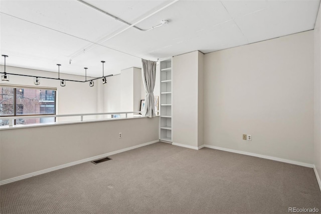 carpeted spare room with visible vents and baseboards