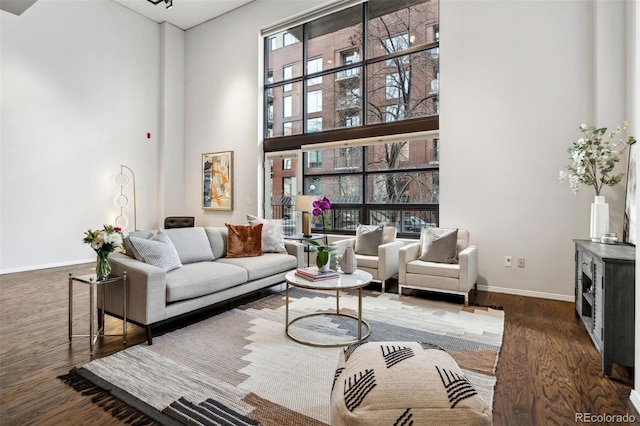 living room with dark wood-style floors, a high ceiling, and baseboards