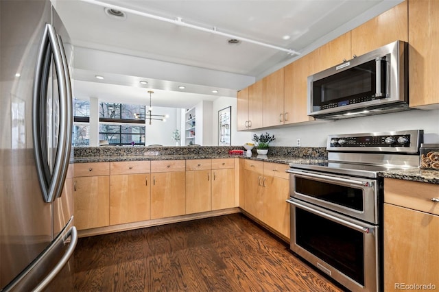 kitchen featuring stainless steel appliances, light brown cabinetry, dark wood-style floors, a chandelier, and dark stone counters