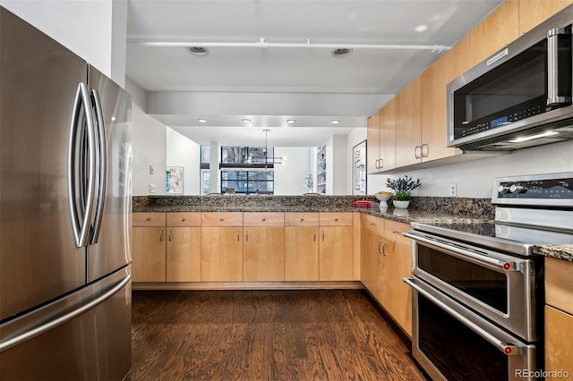 kitchen with appliances with stainless steel finishes, dark wood-type flooring, dark stone counters, and light brown cabinetry