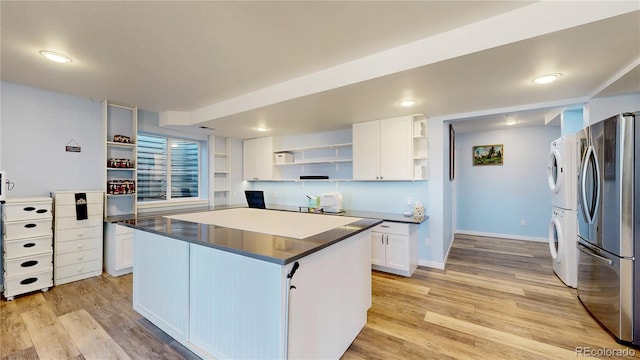 kitchen featuring stacked washer and clothes dryer, freestanding refrigerator, light wood-style floors, and open shelves