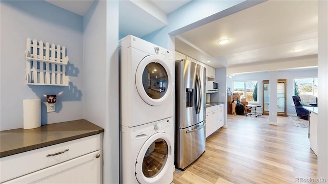 laundry area featuring light wood-style floors, stacked washer and clothes dryer, laundry area, and ornate columns