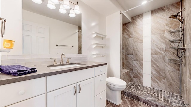 full bathroom with toilet, vanity, and a tile shower