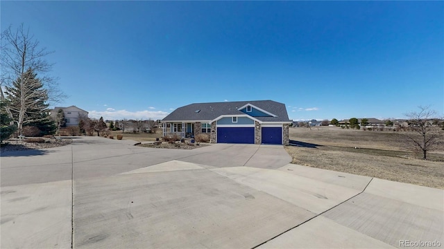 view of front of home featuring a garage, stone siding, and driveway