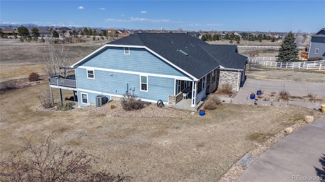 back of property featuring cooling unit, a shingled roof, and fence