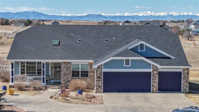 view of front facade with a mountain view, covered porch, roof with shingles, and an attached garage