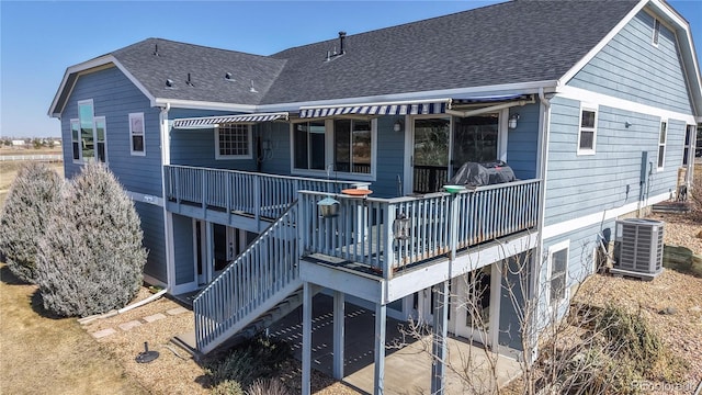 rear view of house with a deck, central air condition unit, stairs, and a shingled roof