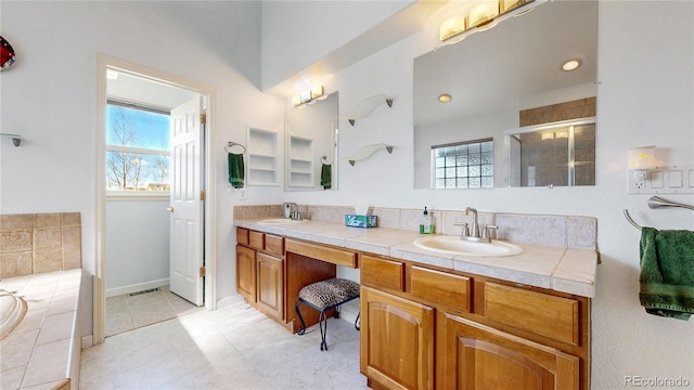 full bathroom featuring double vanity, a bath, a stall shower, and a sink