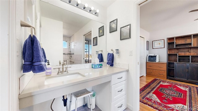 bathroom with wood finished floors, a shower, and a sink