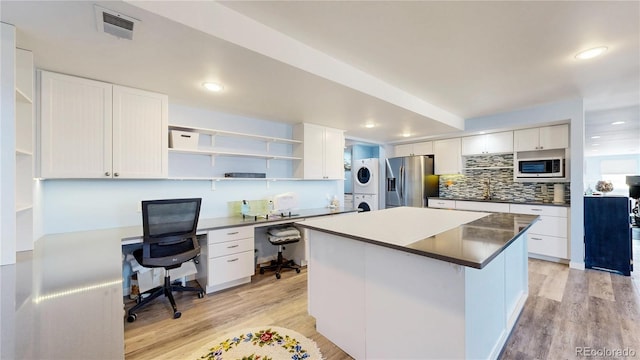 kitchen with visible vents, stainless steel fridge with ice dispenser, built in microwave, stacked washer and dryer, and open shelves