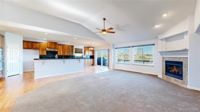 14701 Yosemite St, Brighton, CO 80602 - unfurnished living room featuring lofted ceiling, a ceiling fan, a tiled fireplace, light wood finished floors, and baseboards