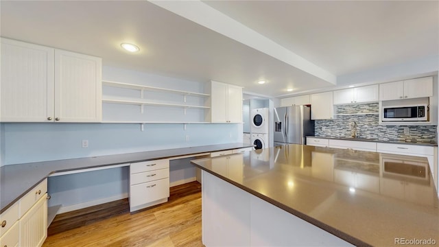 14701 Yosemite St, Brighton, CO 80602 - kitchen with appliances with stainless steel finishes, stacked washer and clothes dryer, dark countertops, light wood finished floors, and recessed lighting