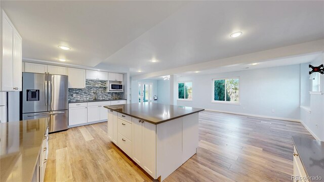 14701 Yosemite St, Brighton, CO 80602 - kitchen featuring stainless steel fridge, dark countertops, white microwave, light wood-style flooring, and recessed lighting