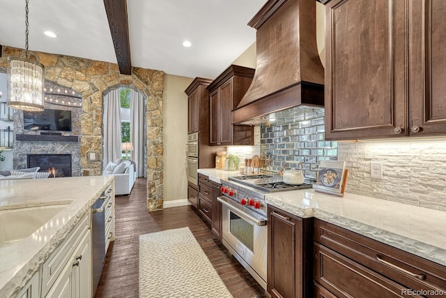 5428 Forest View Rd, Parker, CO 80134 - kitchen featuring appliances with stainless steel finishes, custom range hood, open floor plan, beam ceiling, and light stone counters