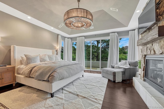 5428 Forest View Rd, Parker, CO 80134 - bedroom featuring a tray ceiling, access to exterior, wood finished floors, a stone fireplace, and a chandelier