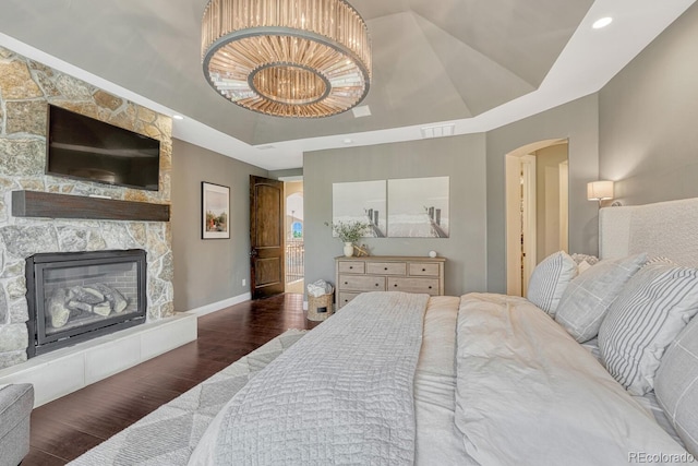 5428 Forest View Rd, Parker, CO 80134 - bedroom with a raised ceiling, wood finished floors, arched walkways, a stone fireplace, and baseboards