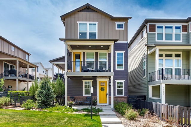 8958 Southurst St, Littleton, CO 80129 - view of front facade featuring a balcony, fence, board and batten siding, and brick siding
