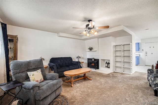 living area with light carpet, a textured ceiling, a wood stove, and ceiling fan