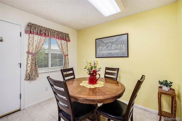 dining space featuring light tile patterned floors, baseboards, and a textured ceiling