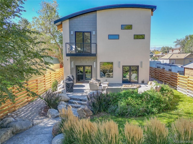 rear view of property with an outdoor living space, a balcony, and a patio