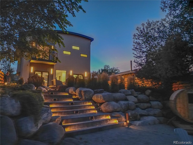 back house at dusk featuring a balcony