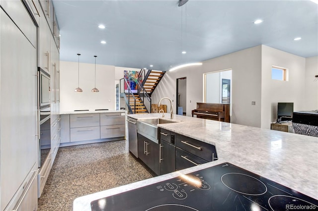 kitchen featuring built in appliances, sink, and hanging light fixtures