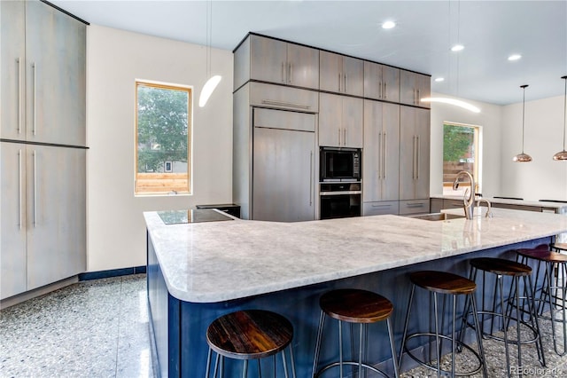 kitchen with black appliances, pendant lighting, a center island with sink, and sink