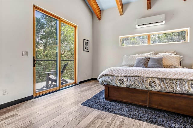 bedroom with access to exterior, beamed ceiling, a wall mounted air conditioner, and light wood-type flooring