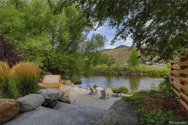 property view of water featuring a mountain view and an outdoor fire pit