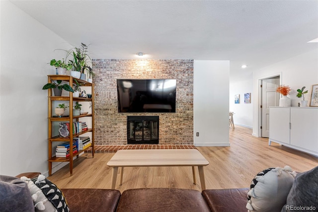 living area featuring light wood-type flooring, a fireplace, and baseboards