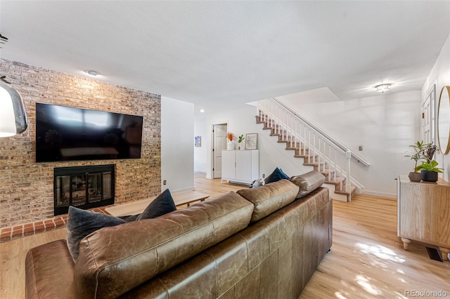 living area featuring a fireplace, stairway, baseboards, and wood finished floors