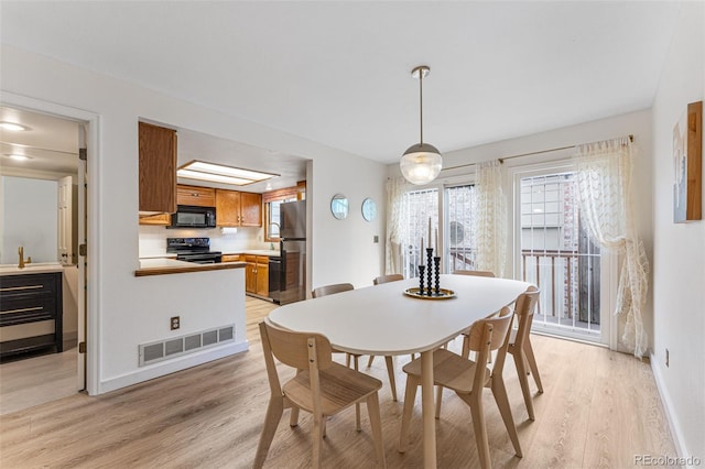 dining space with light wood-type flooring, baseboards, and visible vents