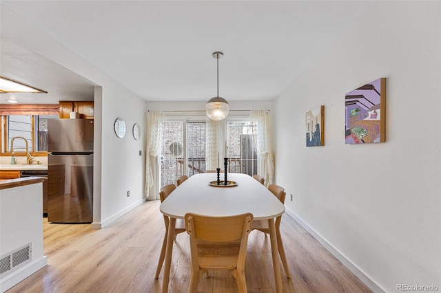 dining space featuring baseboards, visible vents, and light wood finished floors