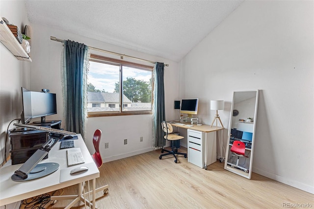 office space featuring light wood-style floors, baseboards, vaulted ceiling, and a textured ceiling