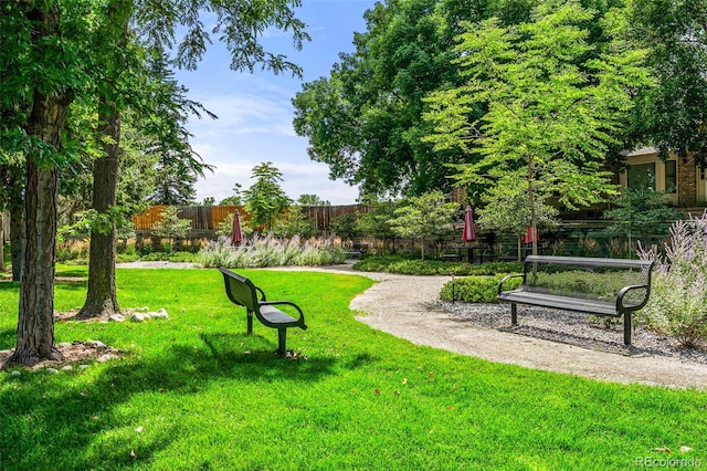 view of home's community with fence and a lawn