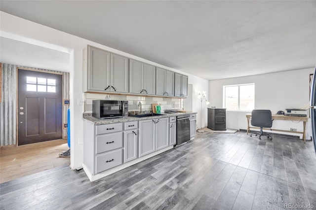 kitchen with a healthy amount of sunlight, black microwave, a sink, and wood finished floors