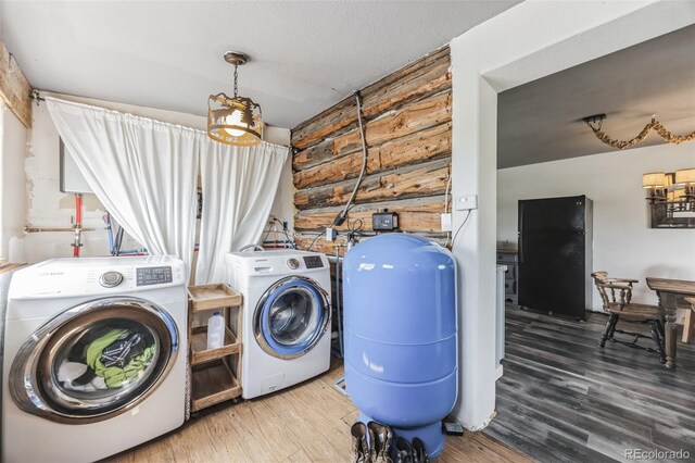 laundry area with a textured ceiling, washer and clothes dryer, and wood finished floors