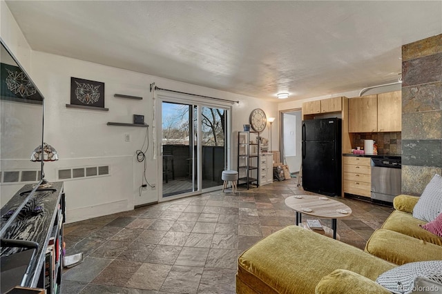 living room featuring baseboards, visible vents, and stone tile floors