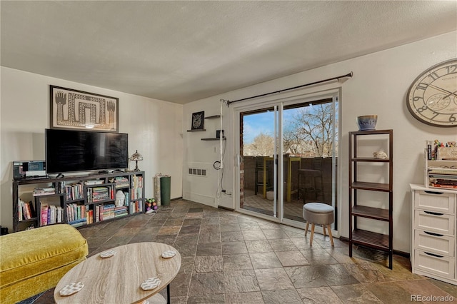 living room featuring a textured ceiling, baseboards, and stone tile flooring
